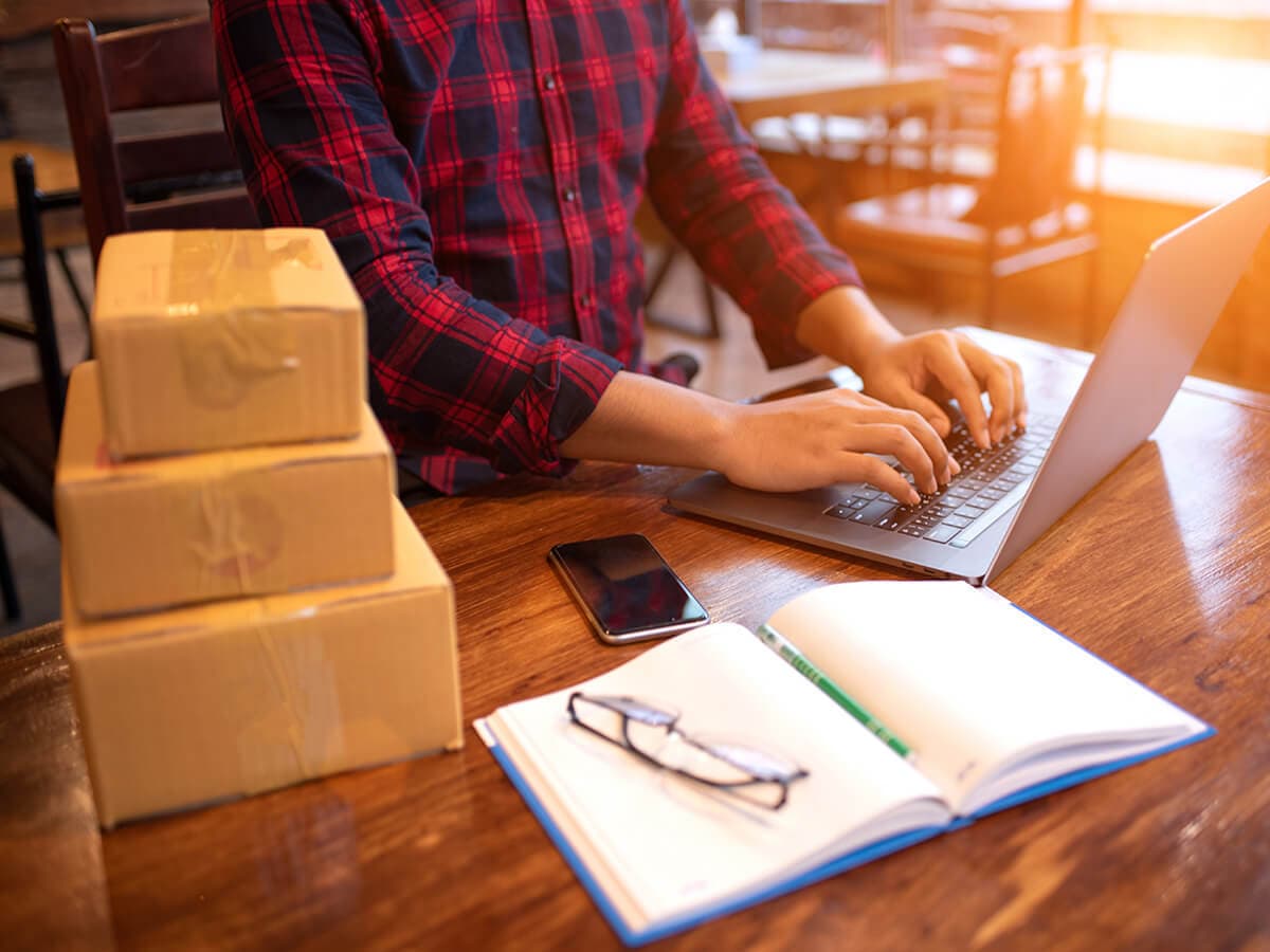 Verpackungslizenzierung Das Wichtigste, Unternehmer bereitet Versand vor, pflegt Daten und Prozesse an einem PC